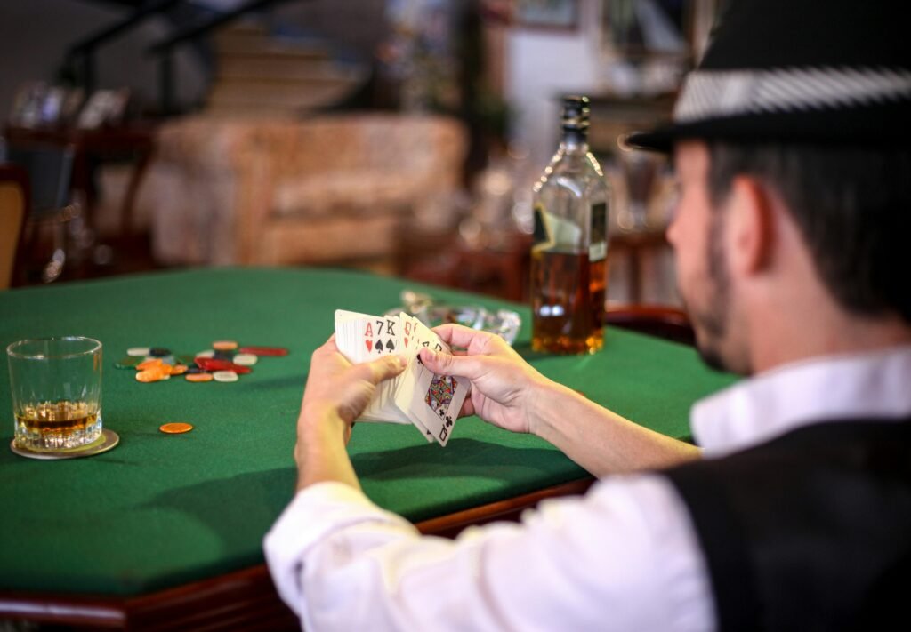 A man holding a poker hand at a casino table with chips and whiskey, conveying a gambling atmosphere.