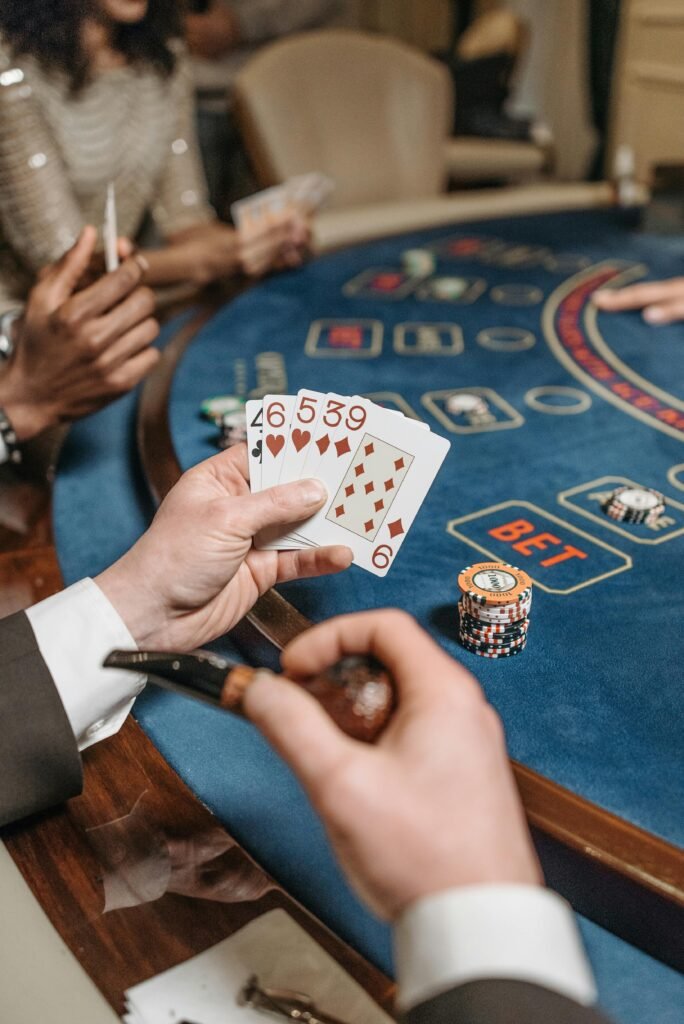 A close-up of players engaged in a poker game at a casino table, showcasing cards and chips.